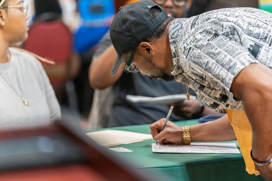 Man signing a sheet at the FIC hiring fair.